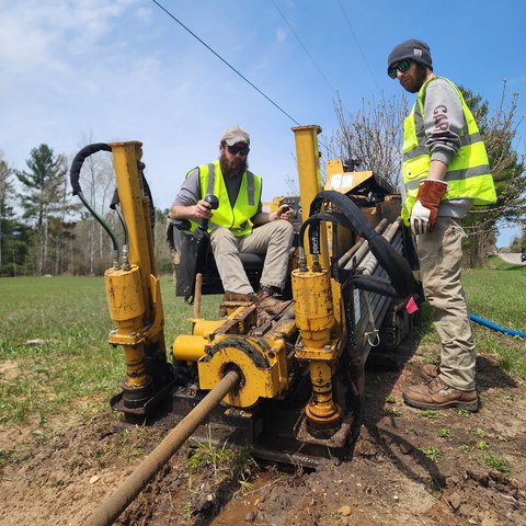Two Eclipse crew members beside a directional drill during underground installation.